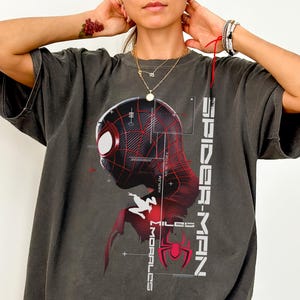 May include: A white ceramic mug with a black handle and the text "But First, Coffee" in a bold, black font. The mug is set against a blurred background, suggesting a cozy setting.