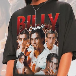 以下が含まれることがあります： 黒いTシャツ。赤色の「BILLY Loomis」の文字と人物のグラフィックが特徴です。デザインはヴィンテージスタイルで、人物の複数の画像が使用されています。背景には、同じ人物のぼやけた画像があります。