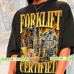 May include: Black t-shirt with a yellow and black graphic featuring a forklift, money, and the words "FORKLIFT CERTIFIED." The shirt has a vintage style with a faded background and the text "DODO DODO" in green.