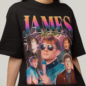 Może przedstawiać: Czarny t-shirt z grafiką w stylu retro Jamesa Acastera, z jego imieniem w kolorowej, vintage czcionce. Projekt zawiera wiele zdjęć komika. Koszulka ma klasyczny okrągły dekolt.