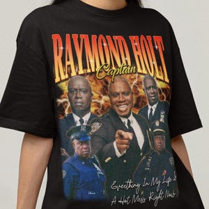 May include: Black t-shirt featuring a graphic of Raymond Holt and other men in police uniforms. The text "RAYMOND HOLT Captain" is above the image, with the phrase "Everything In My Life Is A Hot Mess Right Now" below.