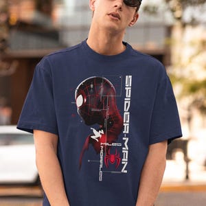May include: Navy blue t-shirt featuring a graphic of Spider-Man's head and torso in red and black, with the text "SPIDER-MAN" and "MILES MORALES" in white. The Spider-Man logo is also visible.