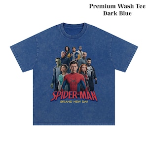 Op de afbeelding: Donkerblauwe t-shirt met een afbeelding van Spider-Man en andere personages. De tekst "SPIDER-MAN BRAND NEW DAY" is in rood en wit gedrukt. Het shirt is gelabeld "Premium Wash Tee Dark Blue".