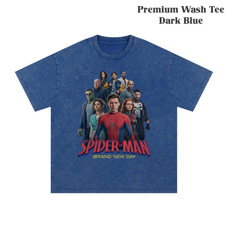 Op de afbeelding: Donkerblauwe t-shirt met een afbeelding van Spider-Man en andere personages. De tekst "SPIDER-MAN BRAND NEW DAY" is in rood en wit gedrukt. Het shirt is gelabeld "Premium Wash Tee Dark Blue".