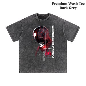 May include: Dark grey premium wash tee featuring a graphic of Spider-Man's head in red and black with the text "SPIDER-MAN" and "MILES MORALES". The shirt has a crew neck and short sleeves.