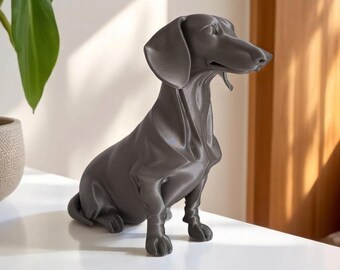 May include: A dark gray dachshund statue in a seated position. The dog figurine has a smooth finish and detailed features, including floppy ears and a long snout. The sculpture is placed on a white surface.