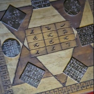 May include: A wooden board with inlaid geometric shapes and metal plaques. The plaques are engraved with symbols and text. The board's colour scheme is light and dark brown, with a border of numbers around the edge. The overall design is intricate.