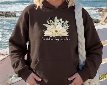 Sweat à capuche « J'écris encore mon histoire », cadeau pour une lectrice passionnée de lecture. Motif floral, style livre, confortable et esthétique.