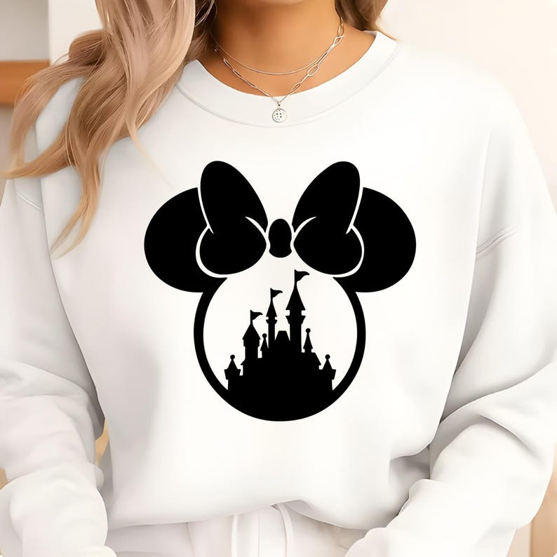 Puede incluir: Sudadera blanca con un lazo negro de Minnie Mouse y la silueta de un castillo. El dise&ntilde;o est&aacute; centrado en la parte delantera de la sudadera. La sudadera tiene cuello redondo y mangas largas.
