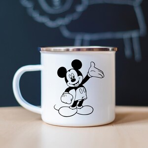 May include: White enamel mug with a silver rim and a black and white illustration of Mickey Mouse. The cartoon character is waving with one hand and smiling. The mug has a white handle.
