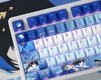 May include: A mechanical keyboard featuring a white frame and a custom keycap set in shades of blue and white. The keycaps display alphanumeric characters, function keys, and decorative anime-style illustrations, including a character on the shift key.