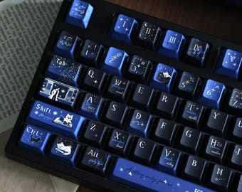 May include: A mechanical keyboard with dark blue and black keycaps featuring white celestial, cat, and literary illustrations. The keys display alphanumeric characters, Roman numerals, and text including 'Shift', 'Ctrl', 'Alt', and 'A story only for us'.