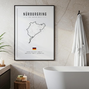Könnte beinhalten: Ein gerahmter Wandkunstdruck mit einer schwarzen Linienzeichnung der Rennstrecke Nürburgring auf weißem Hintergrund. Der Text lautet Nürburgring, The Green Hell, mit einer deutschen Flagge und technischen Details zu Ort und Länge.