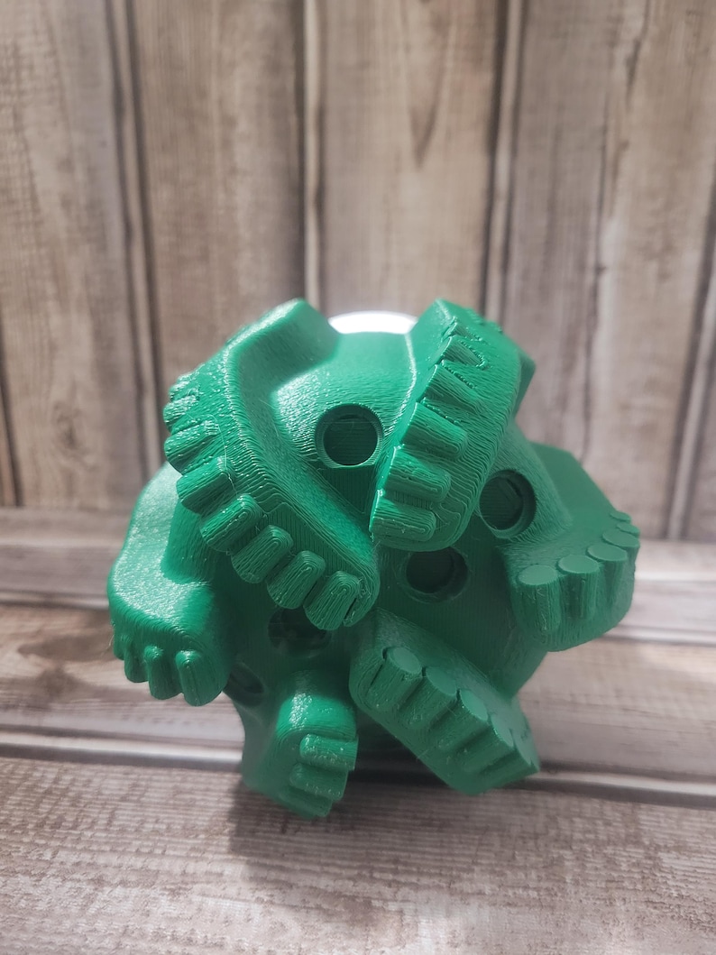May include: A bright green, multi-faceted object with a complex, textured surface. The object has several circular openings and a series of tooth-like protrusions. The item is likely a component or tool, possibly for industrial or construction purposes.