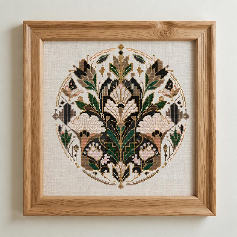 K&ouml;nnte beinhalten: Ein quadratischer Rahmen aus hellem Holz mit einem kreisf&ouml;rmigen Kreuzstich-Stickbild. Das Design zeigt ein symmetrisches Blumenmuster in Dunkelgr&uuml;n, Schwarz, Creme und zartem Rosa, das in einer dichten, komplexen botanischen Anordnung gestaltet ist.
