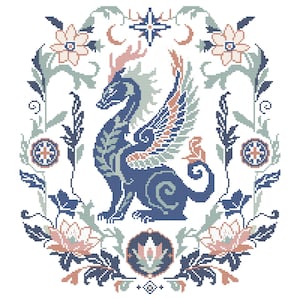 May include: A cross-stitch pattern featuring a central blue dragon with wings, surrounded by a symmetrical floral border in shades of blue, sage green, and soft peach. The design includes stylised leaves, blossoms, and a star at the top.