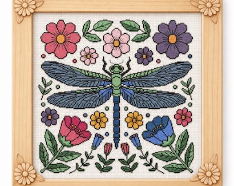 May include: Cross-stitch artwork depicting a dragonfly with blue wings and a green body, surrounded by colourful flowers and green leaves. The piece is framed in a light brown wooden frame with flower corner accents.