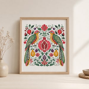 May include: Framed cross-stitch artwork featuring two colorful birds facing each other, with a pomegranate in the center. The design includes red, green, yellow, and purple elements, with fruit and floral motifs. The artwork is in a wooden frame.