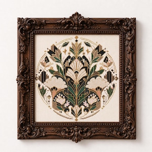 K&ouml;nnte beinhalten: Eine quadratische Kreuzstichstickerei mit einem symmetrischen Blumen- und Geometriemuster in Dunkelgr&uuml;n, Creme, Schwarz und gedecktem Rosa, eingefasst in einen kreisf&ouml;rmigen Rand und in einem verzierten, dunkelbraunen Holzrahmen.