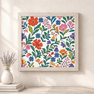 May include: A framed floral cross-stitch pattern featuring a vibrant array of flowers in red, orange, pink, blue, and purple. The design includes green leaves and stems against a white background. The frame is a light wood color.