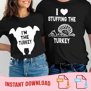 Op de afbeelding: Zwarte t-shirts met witte afbeeldingen. Eén shirt zegt "I'M THE TURKEY" in vette letters in een kalkoenomtrek. Het andere shirt zegt "I HEART STUFFING THE TURKEY" met een kalkoenillustratie. Perfect voor Thanksgiving.