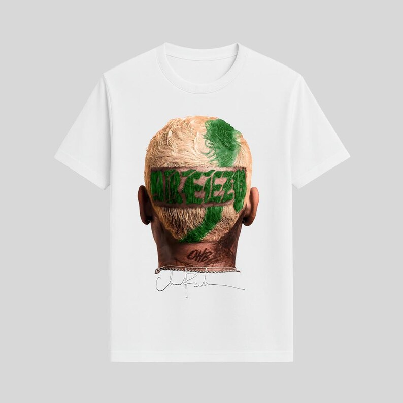 May include: White t-shirt featuring a graphic of a person's head with green text that reads "REEZE" across the back of the head. The person has blonde hair with green streaks. The shirt is a classic crew neck style.