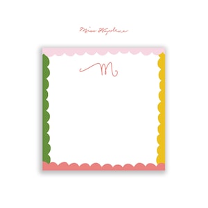May include: A white notepad with a pink, green, and yellow scalloped border. The notepad has the letter "M" written in pink in the top center. The text "Miss Hyolene" is written in pink at the top of the page.