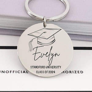 May include: A silver-colored round keychain with a graduation cap illustration and the name "Evelyn". The text "Stanford University Class of 2024" is also displayed. The keychain is attached to a silver ring.