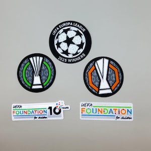 May include: A collection of embroidered patches featuring the UEFA Europa League logo, a soccer ball design, and the text "2025 WINNERS." Also included are patches with the UEFA Foundation logo and the text "10 YEARS."