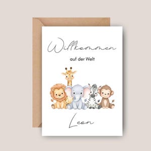 Könnte beinhalten: Eine Grußkarte mit braunem Umschlag. Die Karte zeigt eine Aquarellillustration eines Löwen, einer Giraffe, eines Elefanten, eines Zebras und eines Affen. Der Text auf der Karte lautet "Willkommen auf der Welt" und der Name "Leon".