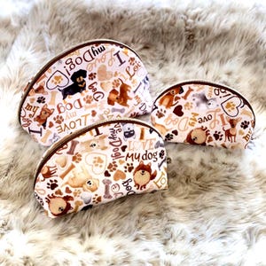 May include: Three cosmetic bags with a white background and a repeating pattern of dog illustrations, paw prints, and the text "I Love My Dog." The bags have brown zips and are in varying sizes.