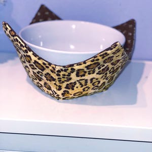 May include: A white ceramic mug with a black handle and the text "But First, Coffee" in a bold, black font. The mug is sitting on a wooden surface. The mug is approximately 4 inches tall.