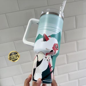 May include: A large, insulated tumbler with a white handle and a straw. The tumbler features a design of a white wolf-like creature with red accents against a teal and green mountain landscape. A "Premium Quality" sticker is visible.