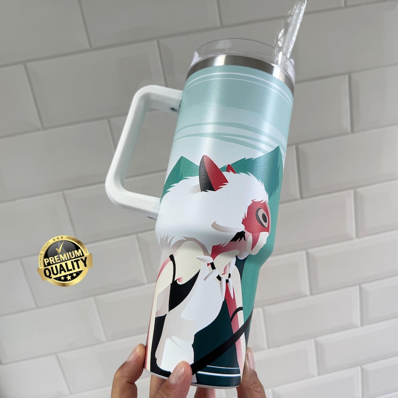 May include: A large, insulated tumbler with a white handle and a straw. The tumbler features a design of a white wolf-like creature with red accents against a teal and green mountain landscape. A "Premium Quality" sticker is visible.