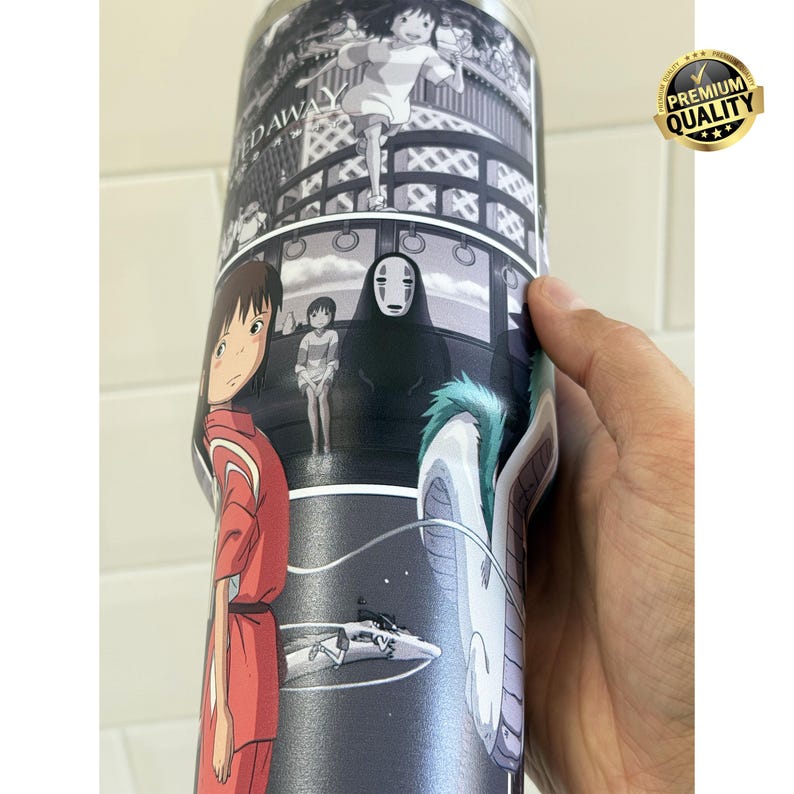 May include: A stainless steel tumbler featuring a black and white anime design. The artwork depicts scenes and characters from a popular animated film. The tumbler is cylindrical and has a glossy finish, with a gold "Premium Quality" sticker.