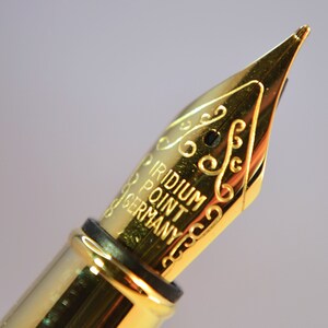 K&ouml;nnte beinhalten: Nahaufnahme einer goldfarbenen F&uuml;llfederhalter-Feder mit der Aufschrift "Iridium Point Germany".