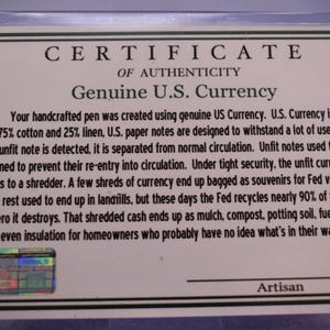 May include: A certificate of authenticity for a handcrafted pen, stating it was made using genuine U.S. currency. The text details the currency's composition of 75% cotton and 25% linen, and the process for handling unfit notes.
