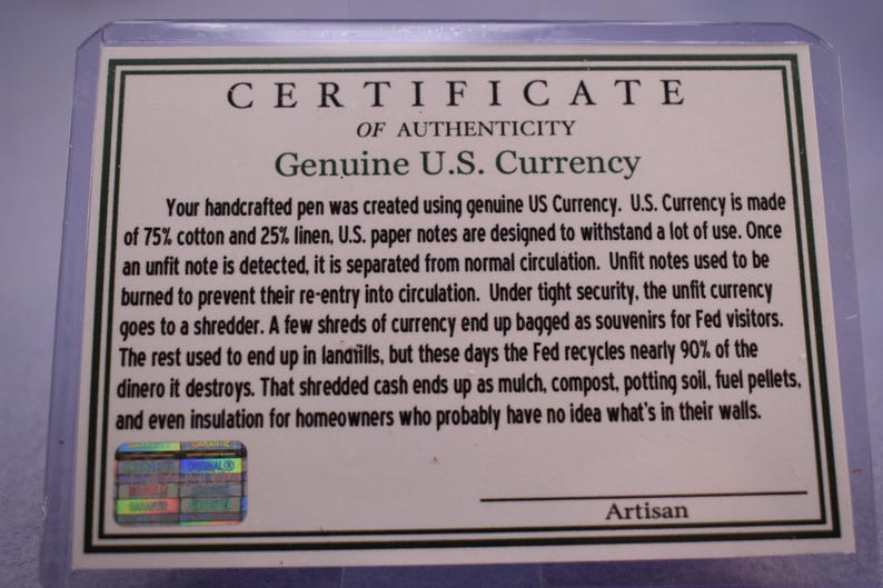 May include: A certificate of authenticity for a handcrafted pen, stating it was made using genuine U.S. currency. The text details the currency's composition of 75% cotton and 25% linen, and the process for handling unfit notes.