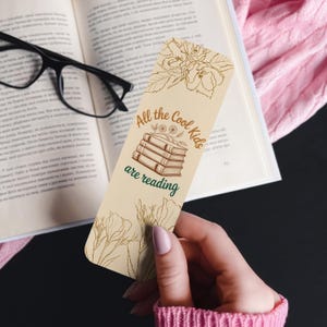 Set of four vintage floral bookmarks featuring botanical line art and reading quotes in neutral tones, displayed on a soft background with daisies and books.