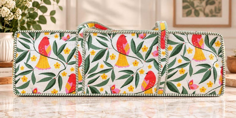 May include: A rectangular fabric storage bag featuring a white background with a repeating pattern of red birds with yellow tails, green leaves, small yellow flowers, and pink butterflies. The bag has two fabric handles and green striped trim.