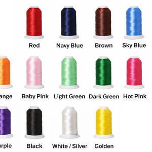 K&ouml;nnte beinhalten: Eine Sammlung von vierzehn Stickgarnspulen, die in drei Reihen angeordnet sind. Die Farben umfassen Rot, Marineblau, Braun, Himmelblau, Orange, Babyrosa, Hellgr&uuml;n, Dunkelgr&uuml;n, Pink, Lila, Schwarz, Wei&szlig;/Silber und Gold.