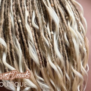 a close-up view of a collection of braided hair strands, with a small white flower or dried plant stem visible next to them.
