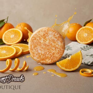 May include: A round orange shampoo bar surrounded by fresh whole oranges, sliced orange segments, and curled orange peels. Liquid splashes around the bar, and the text Harvest Dreads BOUTIQUE is printed in the bottom left corner of the image.