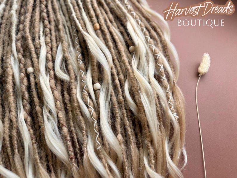 The image showcases a close-up view of a collection of braided and twisted hair strands, with a small white flower resting on the right side. The background is a pinkish-brown color, and there is text in the top right corner that reads "Harvest Dreads Boutique".