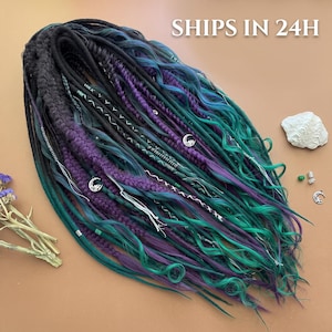May include: A set of synthetic hair extensions featuring a mix of black, deep purple, and teal strands. The bundle includes braided sections, wavy textures, and straight pieces adorned with small silver moon charms and white thread wraps.