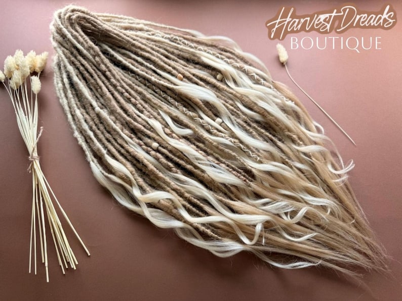 "Handmade in USA sand and vanilla butter blonde synthetic crochet dreadlocks with loose ends and wavy curls by Harvest Dreads Boutique. The set features textured boho dreads decorated with milk chocolate thread wraps and natural wooden beads on a warm background." 🌾