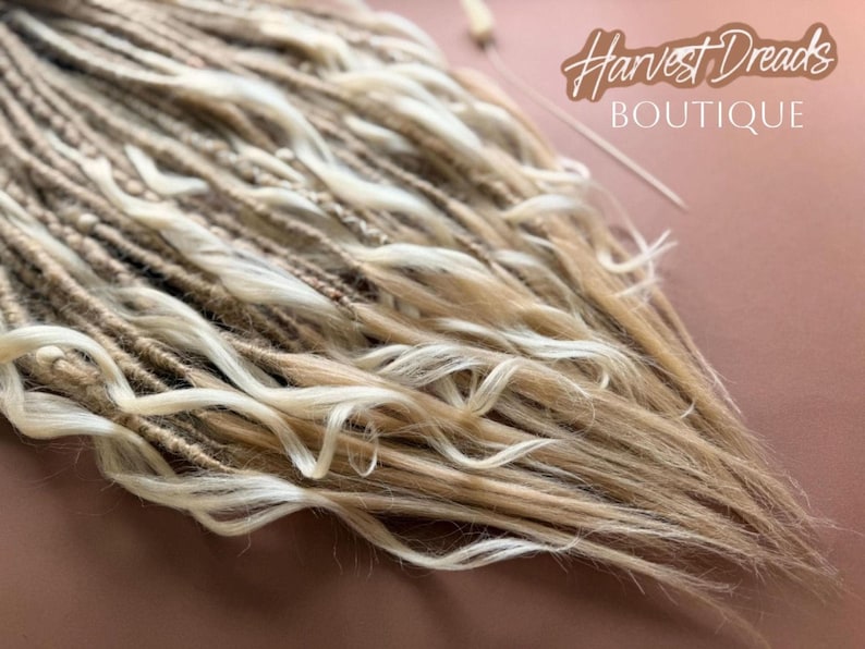 a close-up view of a collection of blonde braided hair strands, with the text "Harvest Dreads Boutique" written in the background.