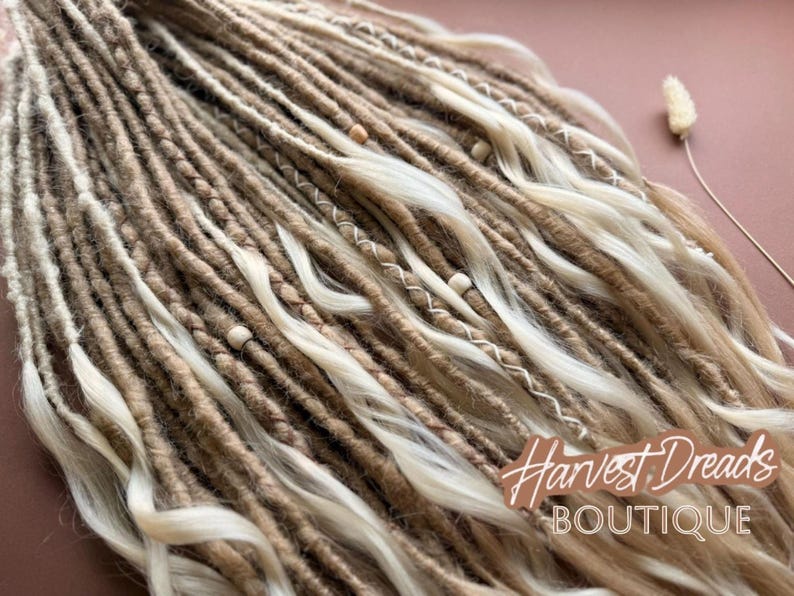 a close-up view of a collection of braided and twisted hair strands, with some beads and a small white flower visible among the strands.