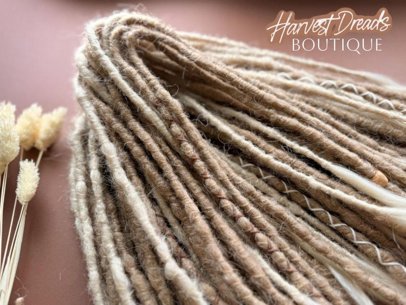 A close-up view of a bundle of brown and beige braided hair, with the text "Harvest Dreads Boutique" written in cursive above it.