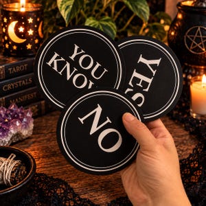 May include: Three circular black coasters with white borders and white text. One coaster reads YOU KNOW, another reads YES, and the third reads NO. The coasters are held together in a stack, displaying the bold, capitalized lettering clearly.